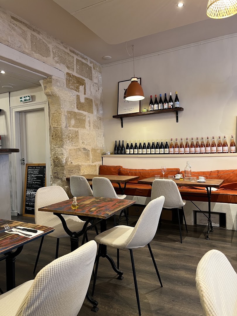La salle en pierre, banquette orange et tables peintes du Bistro 111